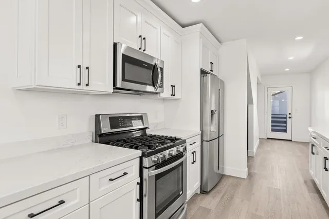 a kitchen with stainless steel appliances white cabinets and a stove a oven with wooden floor