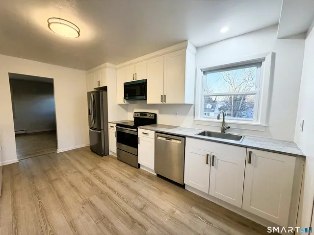 a kitchen with a sink cabinets stainless steel appliances and a window