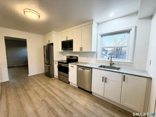 a kitchen with a sink cabinets stainless steel appliances and a window