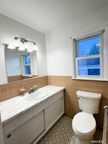 a bathroom with a toilet a sink a mirror and window