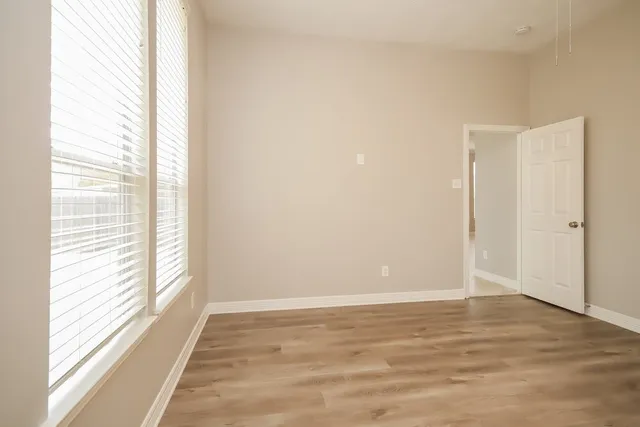 a view of an empty room with wooden floor and a window