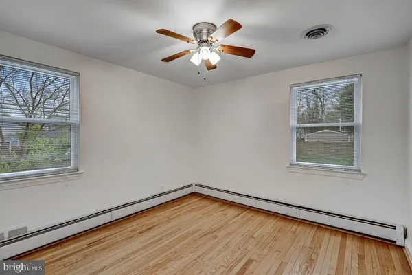 a view of empty room with wooden floor and fan