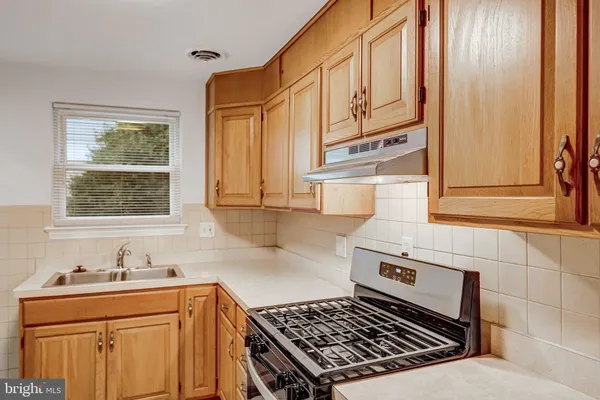 a kitchen with stainless steel appliances a stove a sink and cabinets