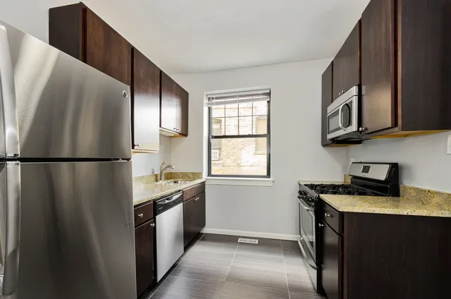 a kitchen with stainless steel appliances granite countertop a refrigerator a stove a sink and a microwave