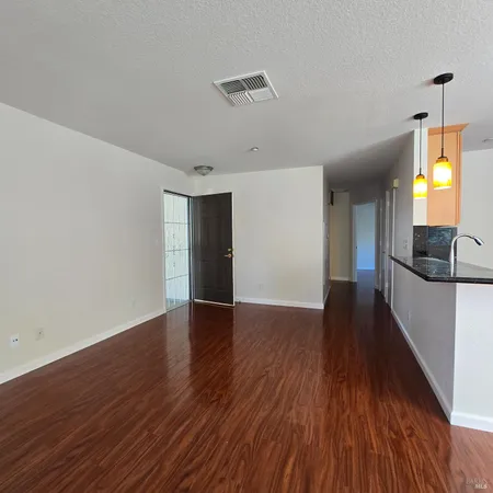 a view of a hallway with wooden floor and a living room