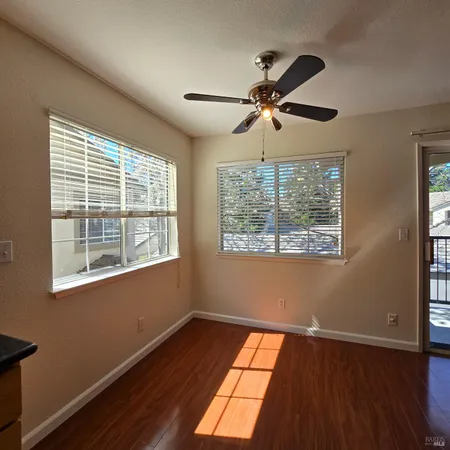 a view of empty room with wooden floor and fan