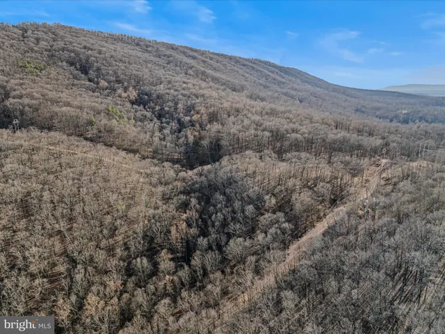 a view of a dry yard with mountains and wooden fence