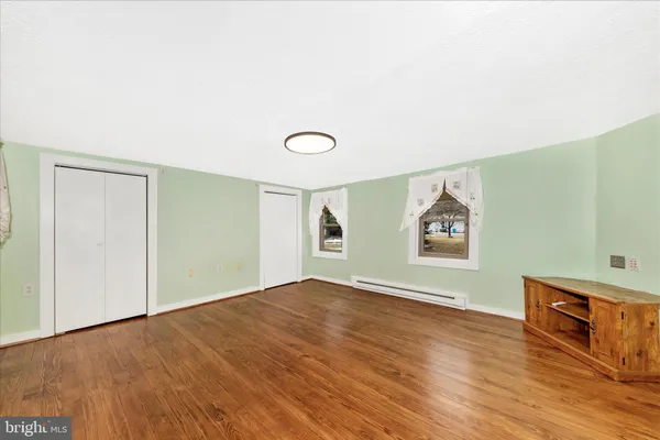 an empty room with wooden floor and window