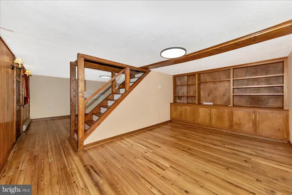 a view of an empty room with wooden floor and stairs