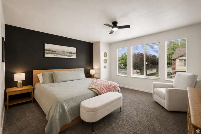 204 Lyman Lane Bountiful, UT 84010 - Photo 8 of 28 Spacious room featuring a dark accent wall, three large windows with blinds, a ceiling fan, and carpeted flooring