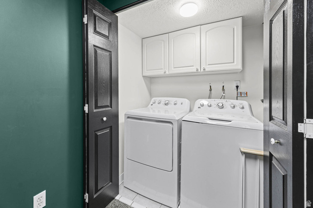 5896 South 3950th Street West Roy, UT 84067 - Photo 20 of 29 Laundry area with cabinet space, a textured ceiling, washer and dryer, and light tile patterned floors
