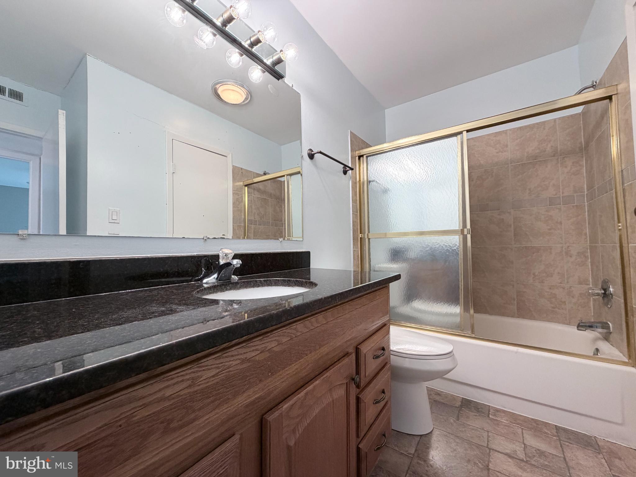 5823 S Royal Ridge Drive Springfield, VA 22152 - Photo 21 of 30 a bathroom with a granite countertop sink a toilet a mirror and bathtub