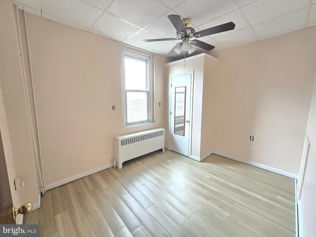 an empty room with wooden floor ceiling fan and windows