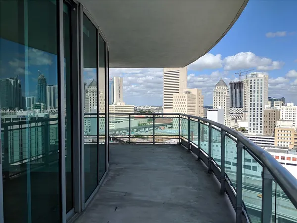 a view of empty room with wooden floor and kitchen