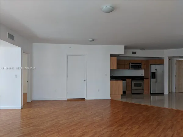 a close view of a refrigerator in kitchen and an empty room