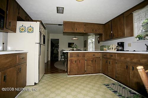 6803 Clifton Forge Road Jacksonville, FL 32277 - Photo 4 of 8 a kitchen with stainless steel appliances granite countertop a refrigerator a sink dishwasher and white cabinets with wooden floor