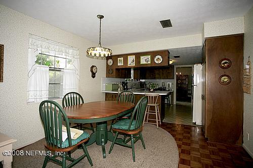 6803 Clifton Forge Road Jacksonville, FL 32277 - Photo 5 of 8 a dining room with furniture a chandelier and wooden floor