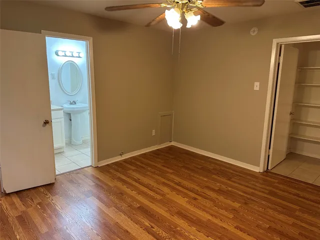 an empty room with wooden floor and fan