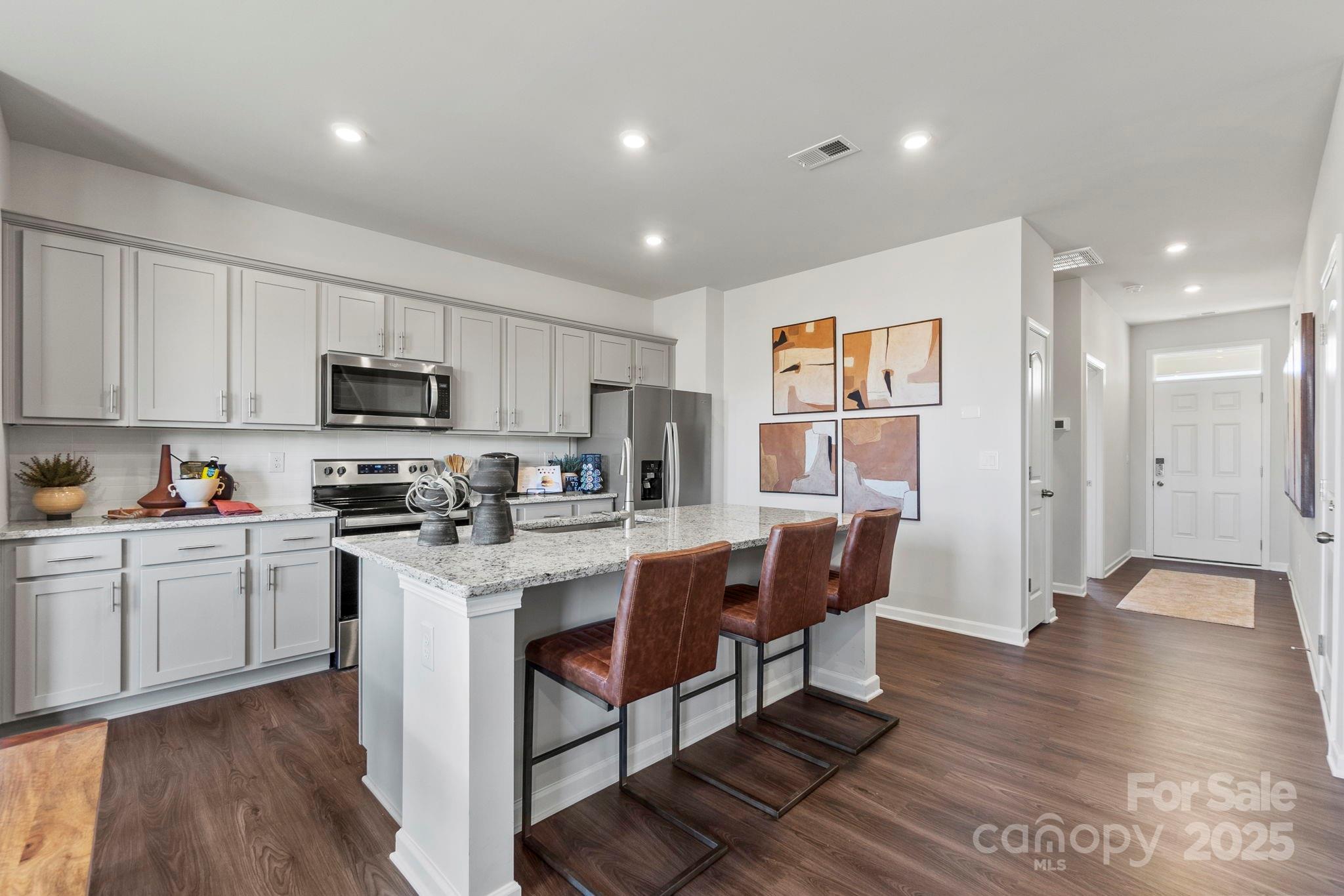 8130 Chilkoot Lane Locust, NC 28097 - Photo 4 of 28 a kitchen with stainless steel appliances granite countertop a refrigerator a stove top oven a sink dishwasher and white cabinets with wooden floor