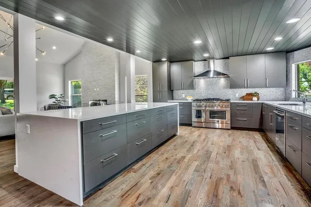 a large kitchen with stainless steel appliances a sink a stove and cabinets