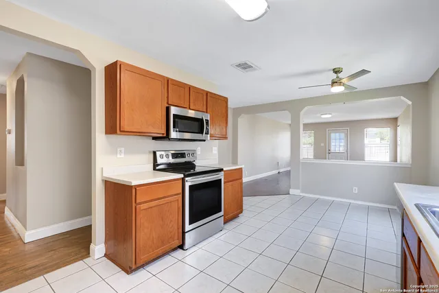 a kitchen with stainless steel appliances granite countertop a stove top oven a sink dishwasher and a refrigerator with wooden floor