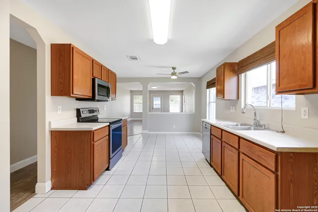 a large kitchen with stainless steel appliances granite countertop a sink counter space cabinets and a large window
