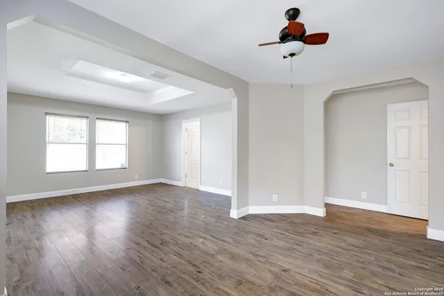 a view of an empty room with wooden floor and a window