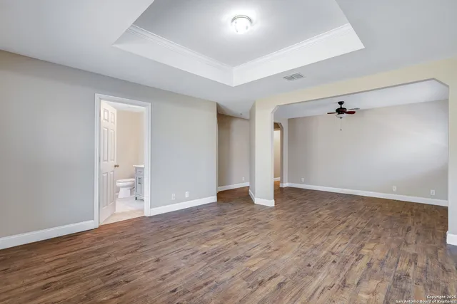 an empty room with wooden floor and ceiling fan