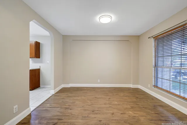 a view of an empty room with a window and wooden floor