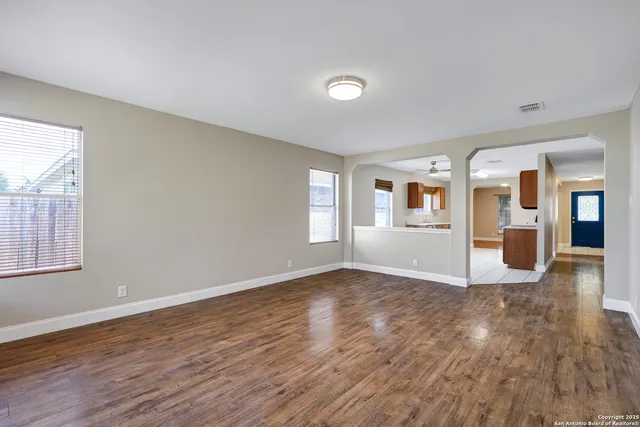 a view of an empty room with window and wooden floor