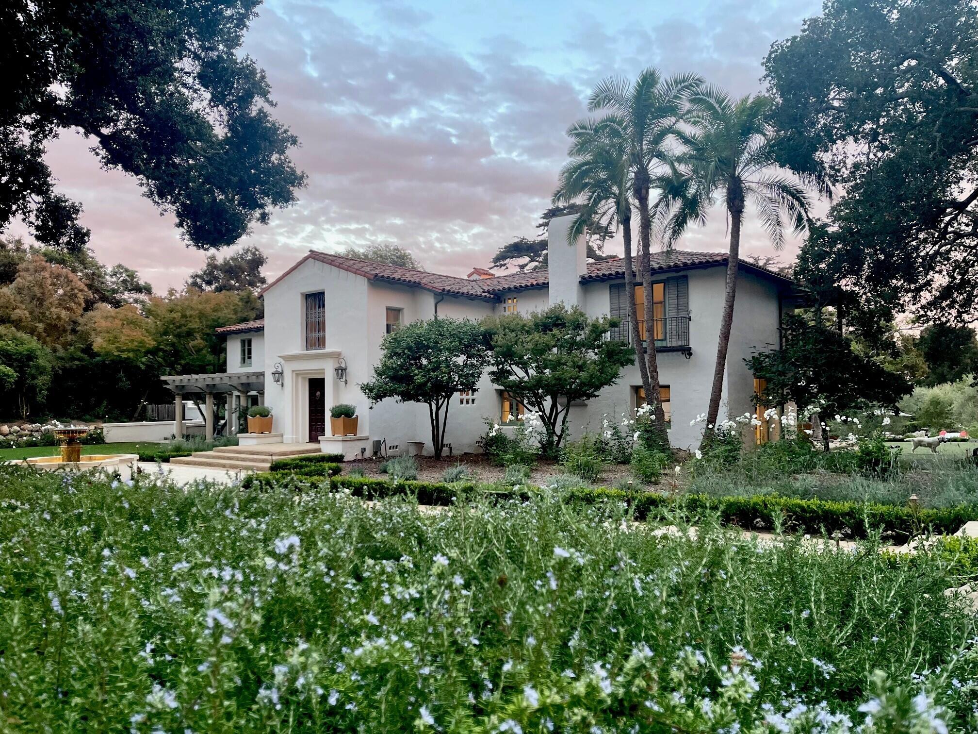 a white house with a large yard and plants