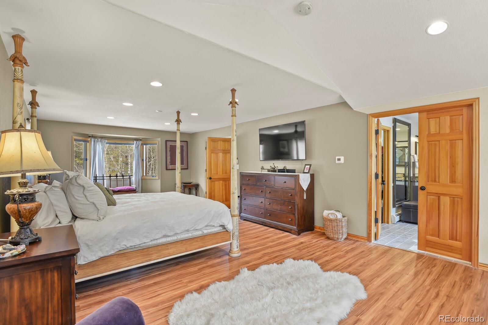 417 Witter Gulch Road Evergreen, CO 80439 - Photo 29 of 50 a bedroom with a bed and wooden floor
