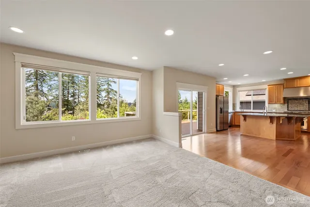 a view of an empty room with kitchen view and a window
