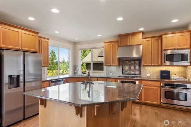 a kitchen with stainless steel appliances granite countertop a sink a stove and a refrigerator