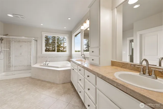 a bathroom with a granite countertop double vanity sink a bathtub and shower