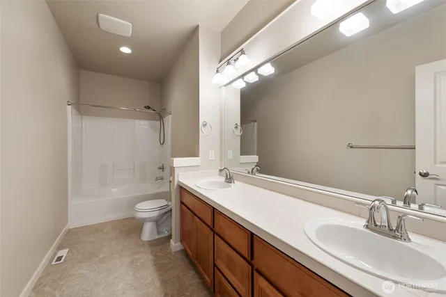 a bathroom with a sink a toilet a mirror and shower