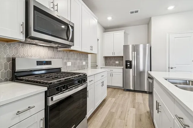 a kitchen with stainless steel appliances granite countertop a stove microwave and refrigerator
