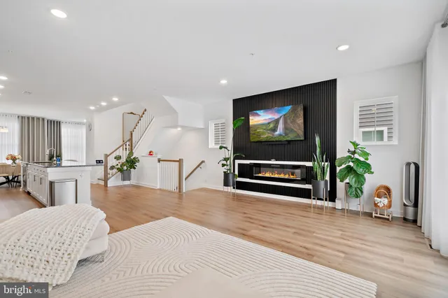 a living room with furniture a kitchen and a wooden floor