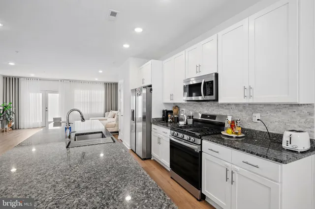 a kitchen with stainless steel appliances granite countertop a stove a sink and a microwave
