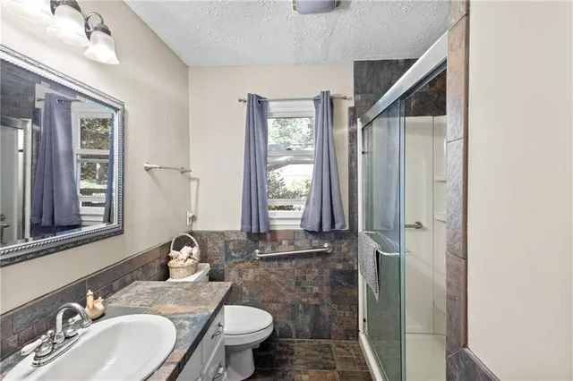 a bathroom with a granite countertop sink toilet and shower