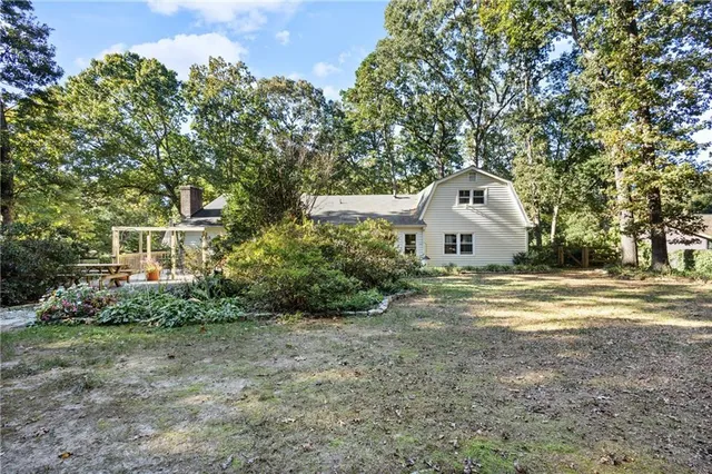 a view of a white house with a yard and large trees