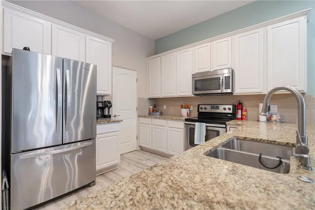 a kitchen with stainless steel appliances granite countertop a refrigerator stove a sink and a microwave