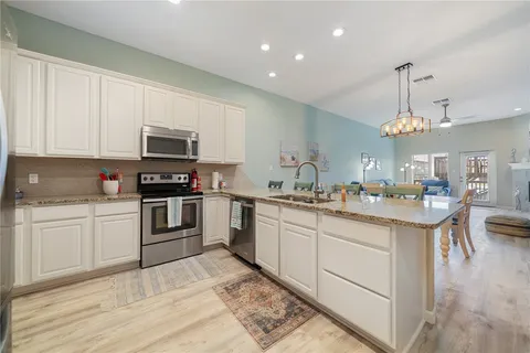 a kitchen with kitchen island granite countertop a sink cabinets and stainless steel appliances