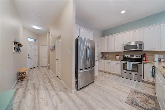 a kitchen with granite countertop a refrigerator and a stove top oven