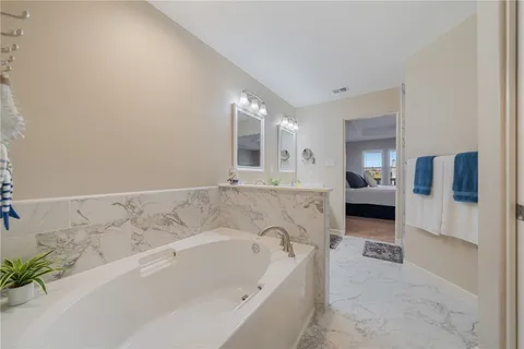 a spacious bathroom with a tub sink and mirror