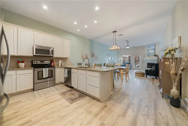 a kitchen with stainless steel appliances granite countertop a refrigerator oven a sink dishwasher and white cabinets with wooden floor