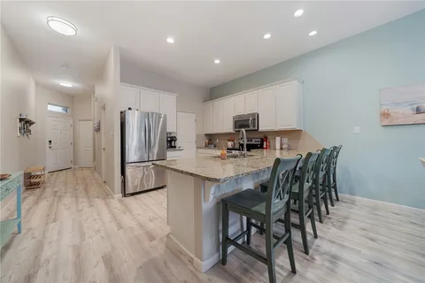 a kitchen with stainless steel appliances a dining table chairs and wooden floor