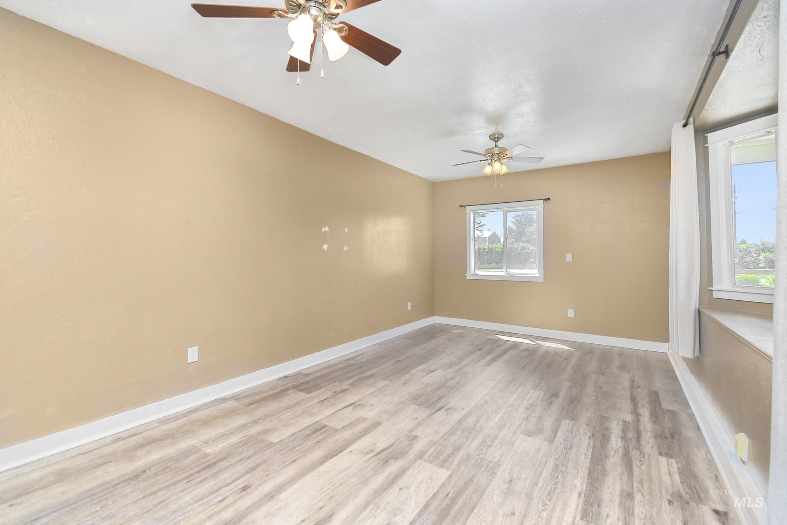 1108 East Ustick Road Caldwell, ID 83607 - Photo 15 of 30 Spacious room featuring wood-finish flooring, two ceiling fans, multiple windows, and neutral wall tones