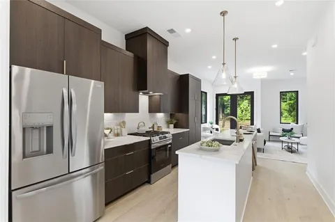 a kitchen with stainless steel appliances a refrigerator a stove a sink and chairs