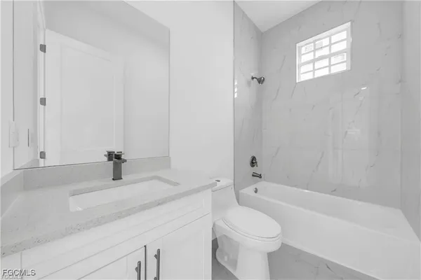 a bathroom with a granite countertop toilet a sink and a bathtub